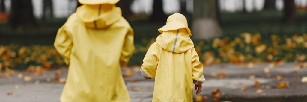 Dwoje dzieci na deszczu w płaszczach przeciwdeszczowych. Przegląd tkanin wodoodpornych. Przewodnik po materiałach odpornych na deszcz