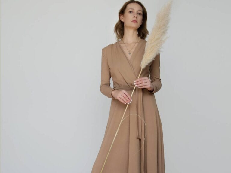 Kobieta w beżowej sukience. Obrazek w artykule Wiskoza co to za materiał? Poznaj jej produkcję, właściwości i zastosowanie